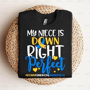 May include: Black t-shirt with a white graphic that says "My niece is down right perfect" with a yellow and blue ribbon symbol. The text "#DownSyndromeAwareness" is at the bottom of the graphic.