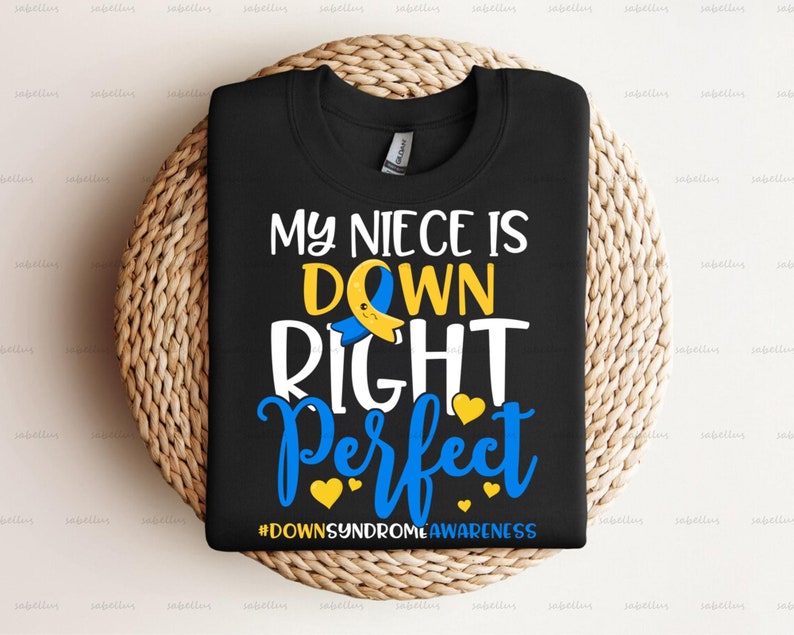 May include: Black t-shirt with a white graphic that says "My niece is down right perfect" with a yellow and blue ribbon symbol. The text "#DownSyndromeAwareness" is at the bottom of the graphic.