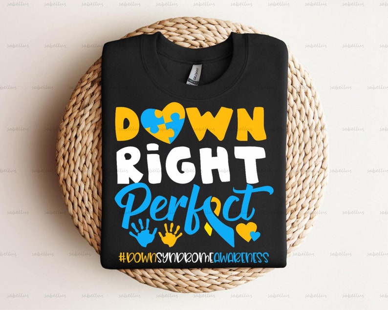 May include: Black t-shirt with a yellow and blue puzzle piece heart, the words "DOWN RIGHT PERFECT" in white, and the hashtag "#DOWNSYNROMEAWARENESS" in white.