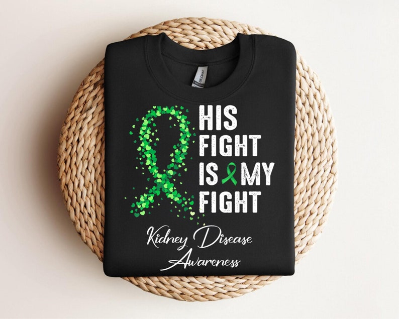 May include: Black t-shirt with a green ribbon design and the text "His Fight Is My Fight Kidney Disease Awareness".