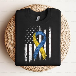 May include: Black t-shirt with a distressed American flag design featuring a yellow and blue ribbon.