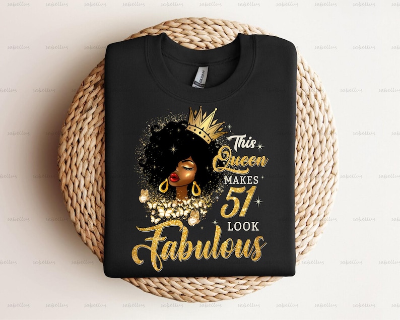 May include: Black t-shirt with a gold crown, a black woman with gold earrings, and the text "This Queen Makes 51 Look Fabulous".