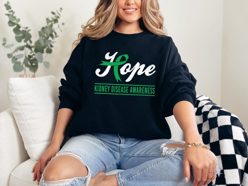 May include: Black sweatshirt with a green ribbon and the word "Hope" in white lettering. The text "Kidney Disease Awareness" is printed below the word "Hope".