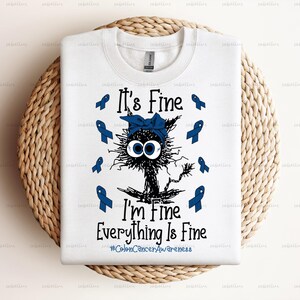 May include: White t-shirt with a blue cartoon cat wearing a blue ribbon. The text "It's Fine I'm Fine Everything Is Fine #ColonCancerAwareness" is printed on the shirt.
