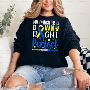 May include: Black sweatshirt with a blue and yellow ribbon and the text "My daughter is down right perfect #DownSyndromeAwareness".