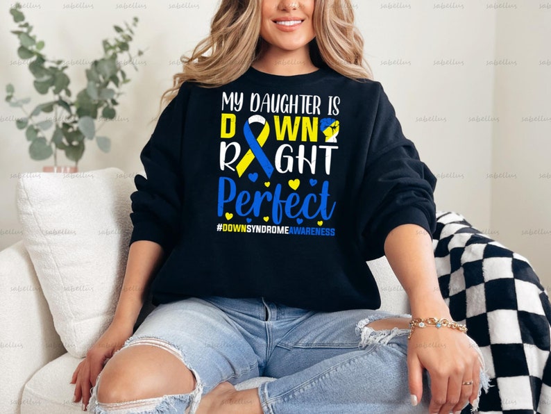May include: Black sweatshirt with a blue and yellow ribbon and the text "My daughter is down right perfect #DownSyndromeAwareness".
