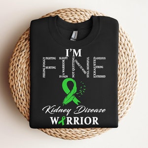 May include: Black t-shirt with a green ribbon and the text "I'm a warrior not quitting" and "Kidney Disease Warrior".