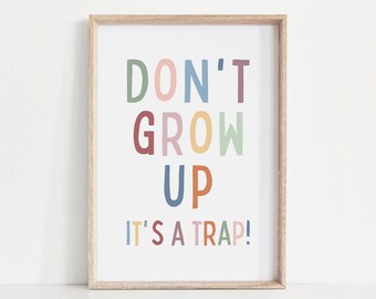 May include: A framed print with the text "Don't grow up, it's a trap!" in colorful letters. The letters are in different colors, including green, pink, blue, red, yellow, and orange.