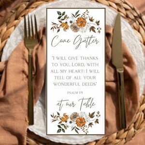 May include: A rectangular table setting card with the words "Come Gather" and "at our Table". The card features floral accents in white, brown, and orange. The text includes a Bible verse from Psalm 1:9.
