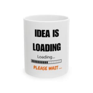 May include: White ceramic mug with the text "IDEA IS LOADING" in black, with "Loading..." and a progress bar below. The words "PLEASE WAIT..." are in orange. A humorous coffee mug.