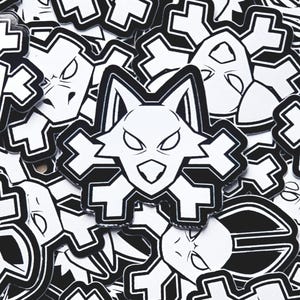 Puede incluir: Una pegatina en blanco y negro con la cabeza de un lobo estilizada con un diseño geométrico. Los ojos del lobo están muy abiertos y la boca está ligeramente abierta. La pegatina está rodeada de otras pegatinas con diseños similares.