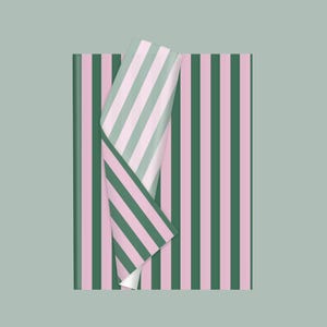 May include: A sheet of wrapping paper featuring a repeating vertical stripe pattern in alternating shades of dark forest green and soft pastel pink. The paper is folded over at the top corner, revealing the reverse side with a lighter green stripe.