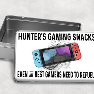 May include: A silver metal tin with a white label that says "HUNTER'S GAMING SNACKS EVEN THE BEST GAMERS NEED TO REFUEL!!" and a cartoon image of a Nintendo Switch.