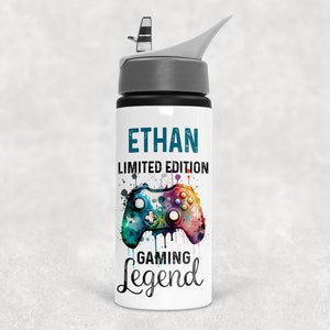 May include: A white water bottle with a black lid and a grey spout. The bottle has a colourful graphic of a video game controller with the text "Ethan Limited Edition Gaming Legend".