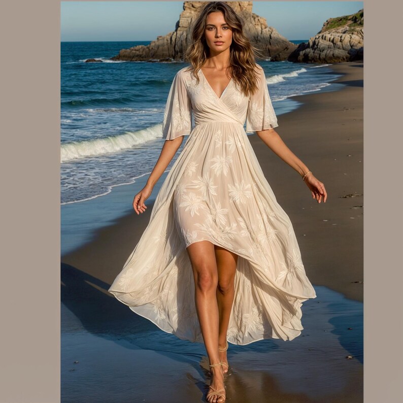 May include: A white maxi dress with a floral print and a high-low hemline. The dress has a V-neckline and short sleeves. The model is wearing the dress on a beach.