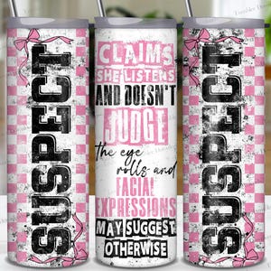 Op de afbeelding: Een witte tumbler met een roze en wit geruit patroon. De tumbler heeft de tekst "SUSPECT" in zwart aan de linkerkant en de tekst "CLAIMS SHE LISTENS AND DOESN'T JUDGE The eye rolls and FACIAL EXPRESSIONS MAY SUGGEST OTHERWISE" in roze aan de rechterkant.