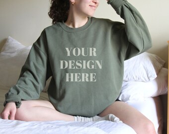 Op de afbeelding: Een groen sweatshirt met de tekst "YOUR DESIGN HERE" erop gedrukt.
