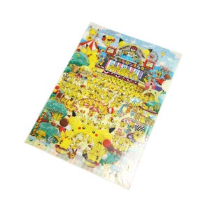 May include: A clear plastic sheet featuring a colorful illustration of Pikachu characters in a festival setting. The image includes a Ferris wheel, stage, and numerous Pikachu figures in various poses, with a blue sky background.