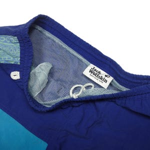 Puede incluir: Ba&ntilde;ador azul y turquesa con forro de malla y una etiqueta de Jack Wolfskin que dice "born to be wild".