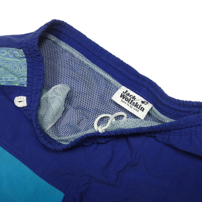 Puede incluir: Ba&ntilde;ador azul y turquesa con forro de malla y una etiqueta de Jack Wolfskin que dice "born to be wild".