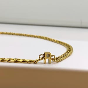 May include: A gold chain necklace with a gold letter 'R' charm.