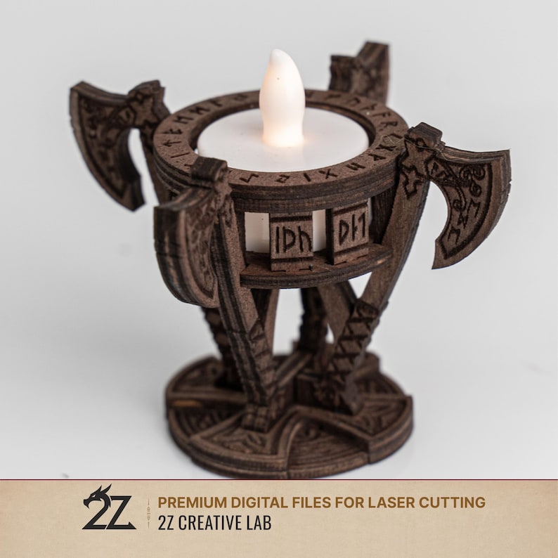 Pu&ograve; includere: Un portacandele in legno marrone scuro con una candela a LED. Il supporto presenta disegni di asce e rune incise. La base ha un design circolare. Il testo "PREMIUM DIGITAL FILES FOR LASER CUTTING" e "2Z CREATIVE LAB" sono in basso.