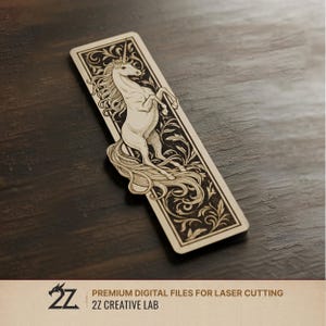 Könnte beinhalten: Ein hölzernes Lesezeichen mit einem lasergeschnittenen Design eines Einhorns. Das Lesezeichen hat einen verzierten Rand mit floralen Mustern. Der Text "PREMIUM DIGITAL FILES FOR LASER CUTTING" und "2Z CREATIVE LAB" befindet sich unten.