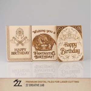 May include: Three wooden birthday cards with laser-cut designs. One card features a helmet and crossed axes, another a dragon, and the third a crown. Each card has the words "Happy Birthday" or "Fantastic Birthday" engraved. The cards are light brown.