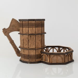 May include: A wooden beer mug with an axe-shaped handle and an attached hexagonal coaster. The mug is made of vertical wooden planks with decorative bands and etched runes. The coaster has an arched railing design. The overall color is brown.