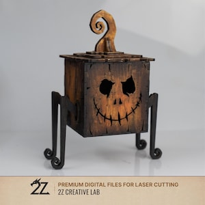 May include: A dark brown wooden box with a carved jack-o'-lantern face, featuring a swirling stem on top and four black metal-like legs. The front panel displays cutouts for eyes, a nose, and a wide, stitched-style grin. Text reads 2Z CREATIVE LAB.