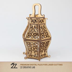 Op de afbeelding: Een houten lantaarn met ingewikkelde, lasergesneden ontwerpen. De lantaarn heeft een handvat en decoratieve voetjes. De tekst "PREMIUM DIGITAL FILES FOR LASER CUTTING" en "2Z CREATIVE LAB" zijn zichtbaar. De lantaarn is gemaakt van lichtbruin hout.