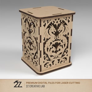 Puede incluir: Una caja de madera de color claro con intrincados diseños de dragones cortados en los lados. La caja tiene forma cuadrada con tapa y base. El texto "PREMIUM DIGITAL FILES FOR LASER CUTTING" y "2Z CREATIVE LAB" son visibles.