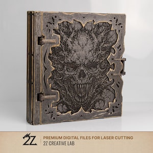 Peut inclure: Un livre en bois avec un motif sculpté détaillé d'un crâne et de motifs complexes. La couverture est gris foncé avec des accents gris plus clairs. Le livre est fermé et possède un fermoir. Le texte "PREMIUM DIGITAL FILES FOR LASER CUTTING" et "2Z CREATIVE LAB" est visible.