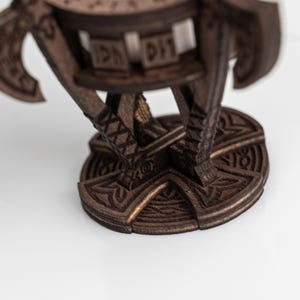 Pu&ograve; includere: Oggetto decorativo in legno marrone scuro con intagli intricati. Presenta una base circolare e una struttura a pi&ugrave; livelli con motivi geometrici e stilizzati. Il design suggerisce un tema storico o fantasy.