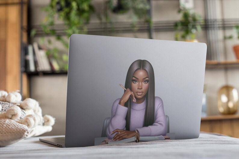 May include: A laptop computer with a sticker of a woman with long black hair wearing a purple sweater and looking thoughtfully at a pencil. The woman is sitting at a desk with a notebook in front of her.