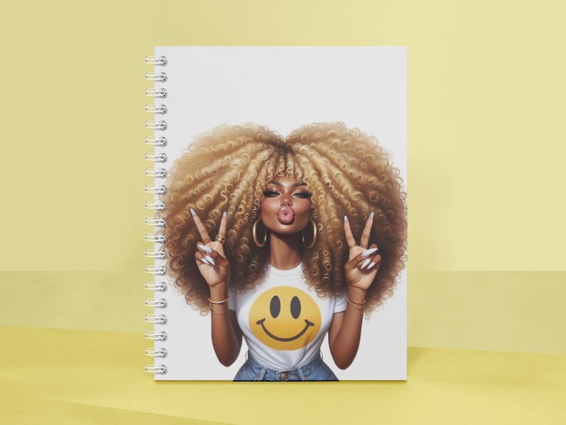 Puede incluir: Cuaderno de espiral con una colorida ilustraci&oacute;n de una mujer con cabello rubio voluminoso, haciendo el signo de la paz. Lleva una camiseta blanca con un emoji amarillo. El cuaderno tiene una cubierta blanca.