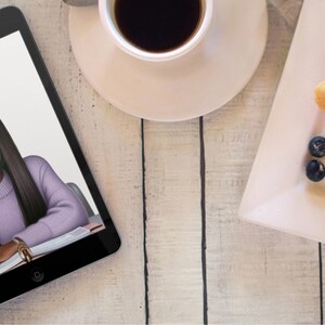 May include: A digital tablet displaying a drawing of a woman with long black hair, wearing a purple shirt and looking at a pencil. The tablet is on a light wood surface.