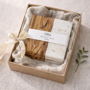 May include: A set of four square coasters, half wood and half marble, presented in a brown gift box with a beige ribbon. The coasters are banded with a white label that reads "MAPLE RAE designs".
