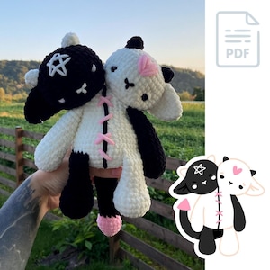 以下が含まれることがあります： 黒と白の2つの編みぐるみが縫い合わされています。白い方はピンクのアクセントと真ん中に縫い付けられた縫い目があります。黒い方は頭に星が付いています。