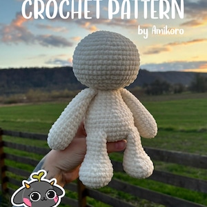 Puede incluir: Muñeca de ganchillo color crema con cabeza redonda y extremidades sencillas. El texto "CROCHET PATTERN by Amikoro" se muestra en la parte superior. El fondo es borroso, con campos y una puesta de sol.