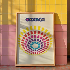 May include: A framed poster with a colorful geometric design in the shape of a sunburst. The poster is on a tiled wall with a white washing machine in the background. The poster says "OAXACA" in blue letters.