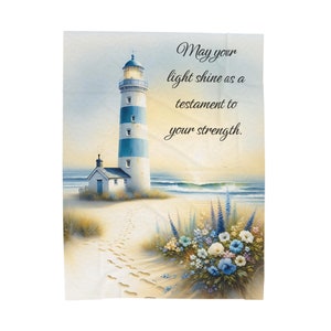 May include: A lighthouse stands tall on a sandy beach with waves crashing in the background. The sky is a soft orange and pink. The text "May your light shine as a testament to your strength." is written in black lettering on a white background.