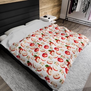 May include: White bedding with a red apple pattern. The apples are whole and sliced, with some leaves and white flowers.