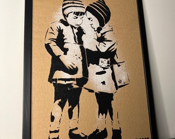 May include: Black and white stencil art print of two children wearing hats and coats, standing close together. The print is on a brown background and signed "Banksy" in the bottom right corner.