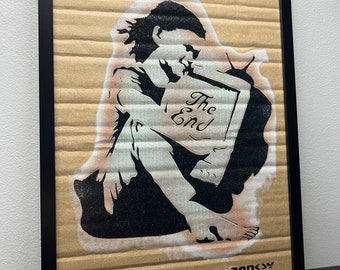 May include: A black and white stencil art print of a person holding a television with the words "The End" written on the screen. The print is on a brown cardboard background and is signed "Banksy" in the bottom right corner.