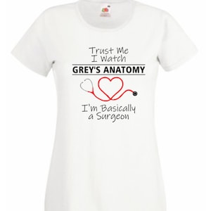 May include: White t-shirt with a black graphic that says "Trust Me I Watch Grey's Anatomy I'm Basically a Surgeon" with a red heart and stethoscope.