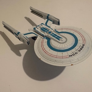 May include: A set of three ceramic mugs with a speckled, matte finish. The mugs are in shades of cream, light gray, and dark gray. Each mug has a simple, minimalist design, perfect for coffee or tea.