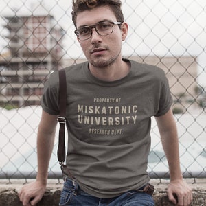 May include: A dark gray t-shirt with the text "PROPERTY OF MISKATONIC UNIVERSITY RESEARCH DEPT." printed in white.