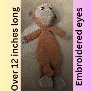 May include: A handmade plush monkey toy, over 12 inches long, with embroidered eyes. The monkey features a brown body, a tan face, ears, hands, and feet. The text "Embroidered eyes" is on the right side of the image.