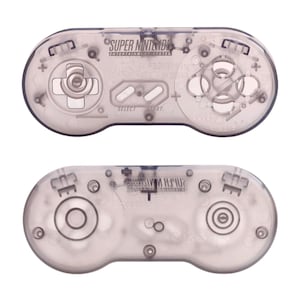 May include: Two Super Nintendo Entertainment System game controllers with a transparent, smoke-colored plastic shell. The top controller displays the directional pad, four action buttons, and Select and Start buttons. The bottom controller shows the reverse side.